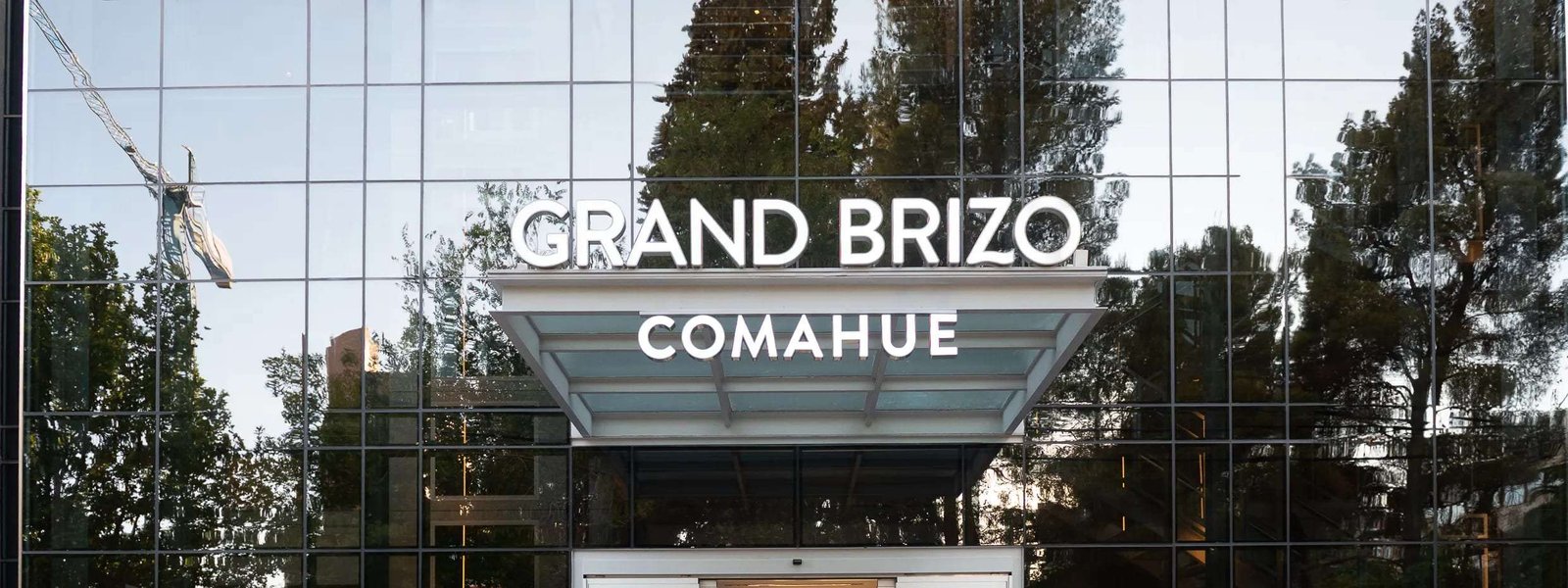 Fachada vidriada del hotel Grand Brizo Comahue en Neuquén Capital, con su cartel sobre la marquesina del acceso