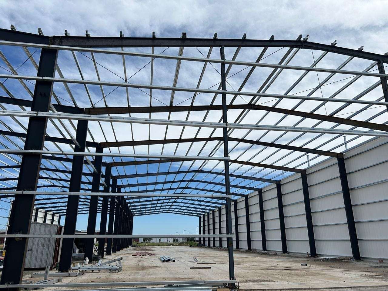 Estructura metálica de una nave con el techo montado y el cerramiento lateral a medio colocar