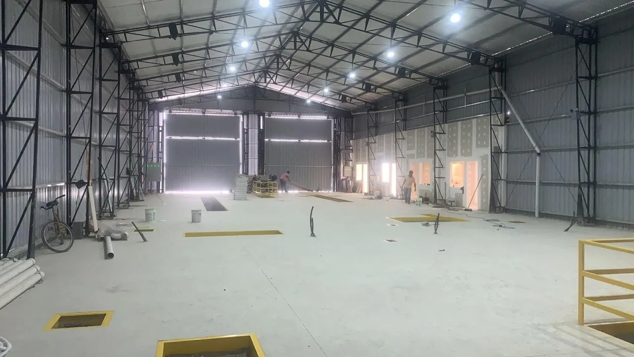 Interior de nave industrial terminada con estructura reticulada, cubierta de chapa e iluminación colocada