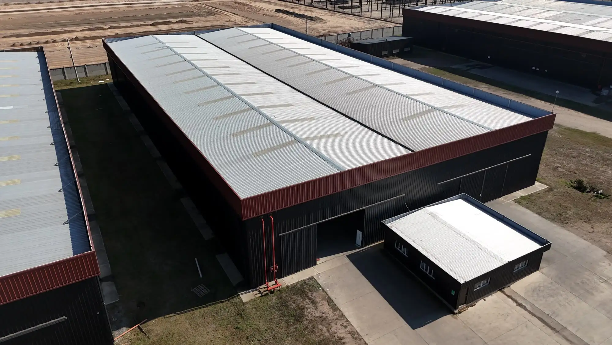 Nave industrial terminada con acceso lateral y vereda perimetral de hormigón
