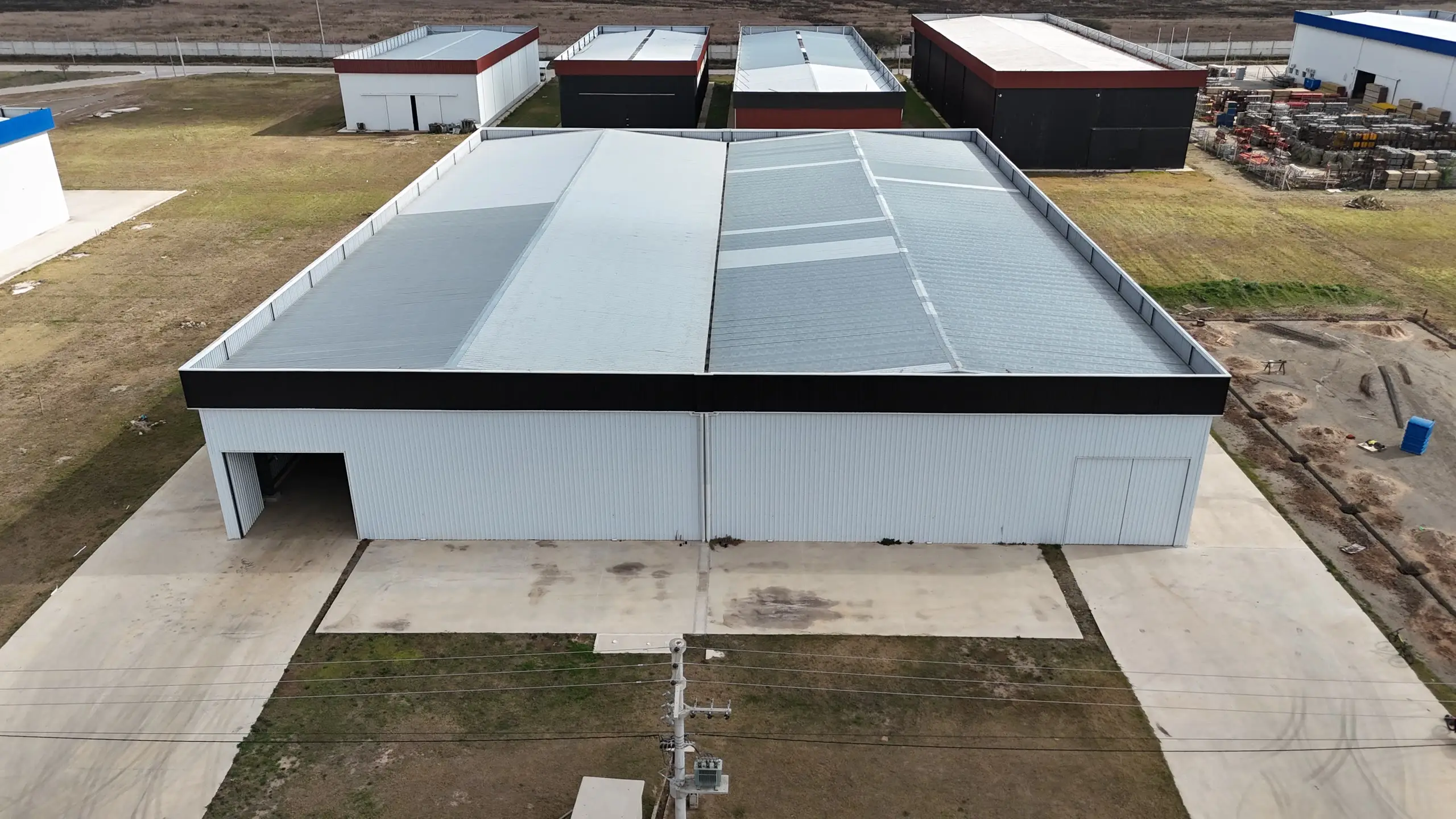 Vista aérea frontal de una nave industrial doble terminada, de dos módulos con chapa traslúcida en la cubierta