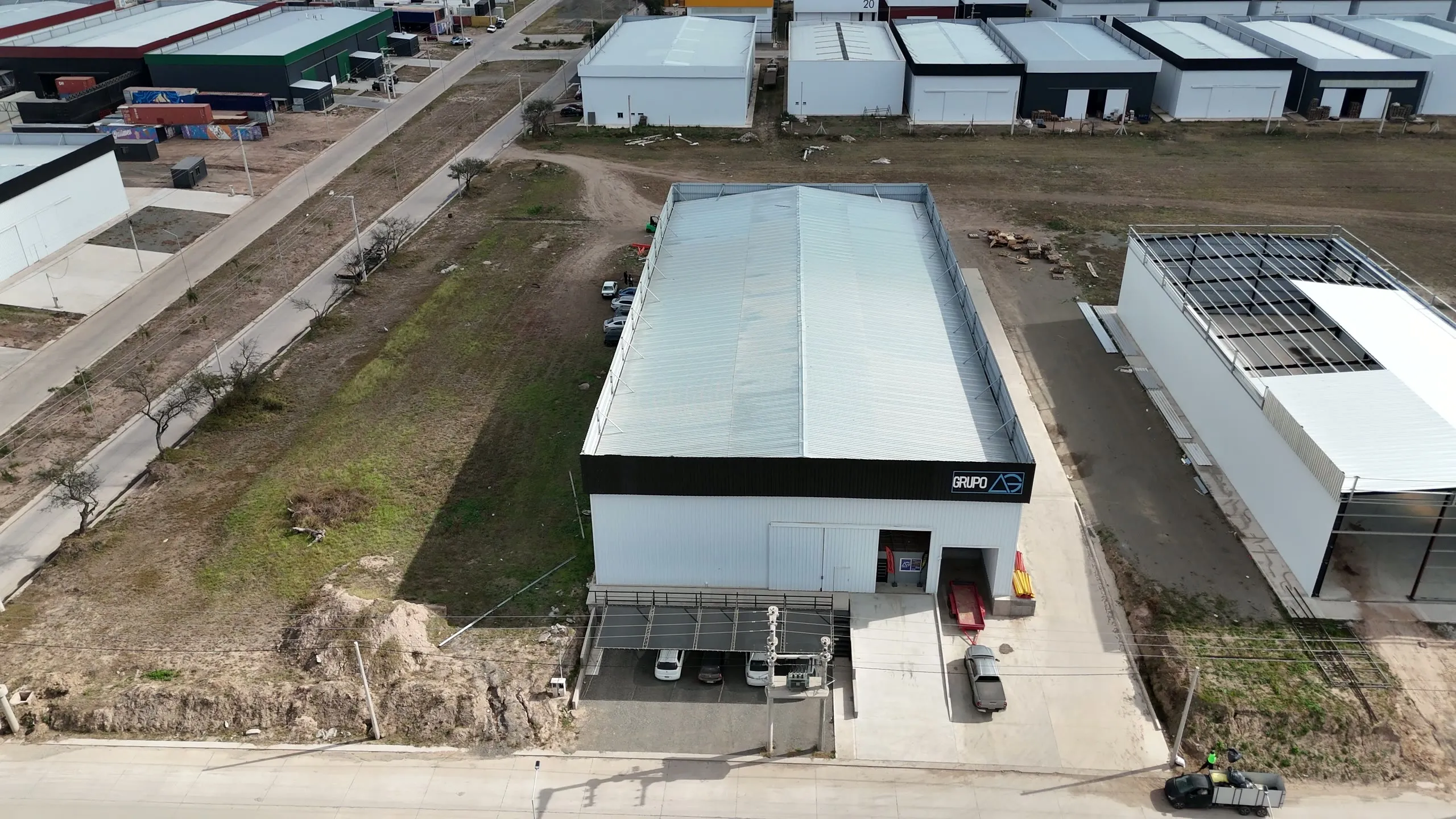 Vista aérea de una nave industrial terminada, con cochera semicubierta en el acceso