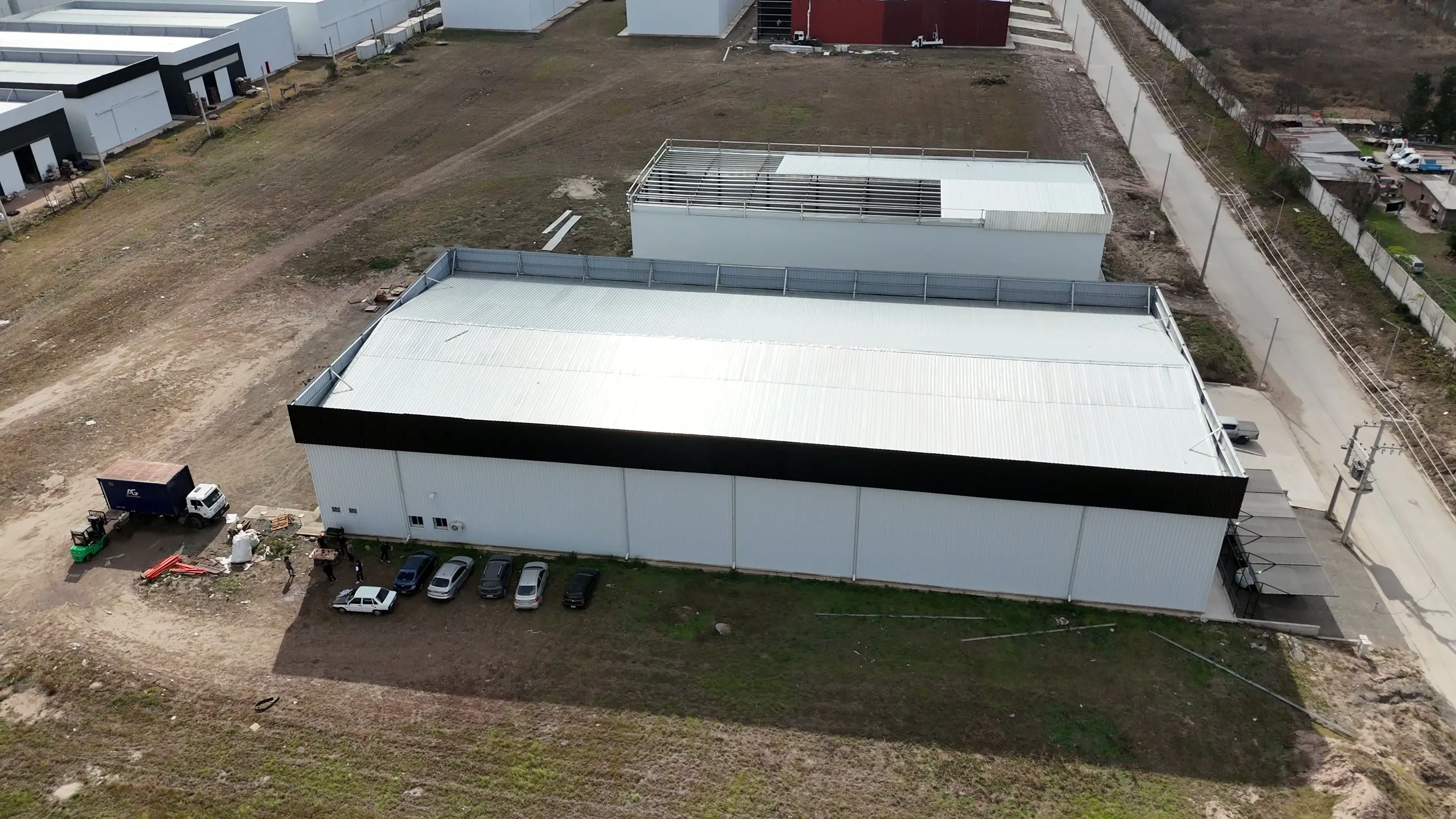 Vista aérea de una nave industrial terminada con banda perimetral negra y cochera semicubierta en el acceso