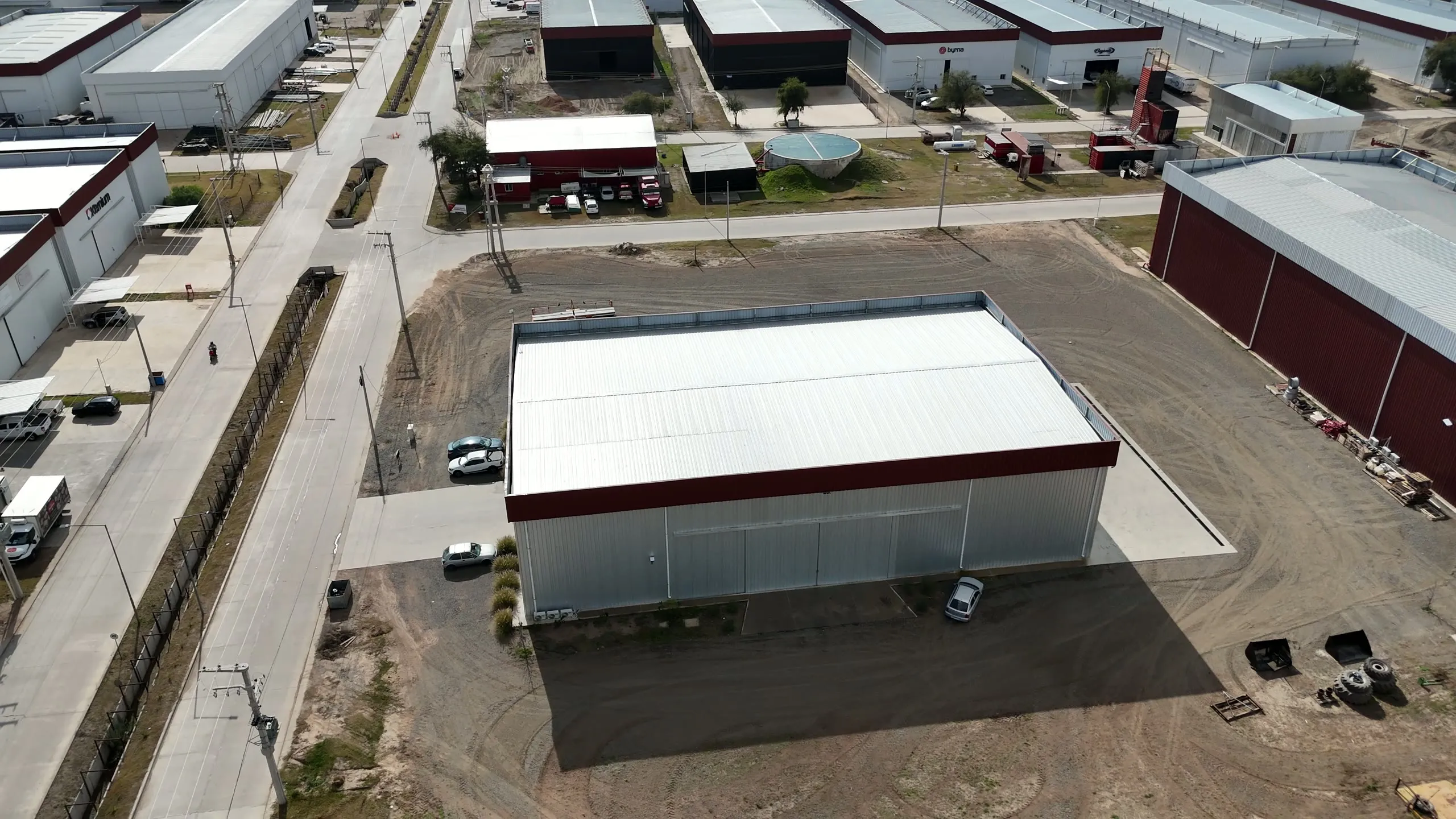 Vista aérea de una nave industrial terminada dentro de un parque industrial, con calles internas y depósito de containers