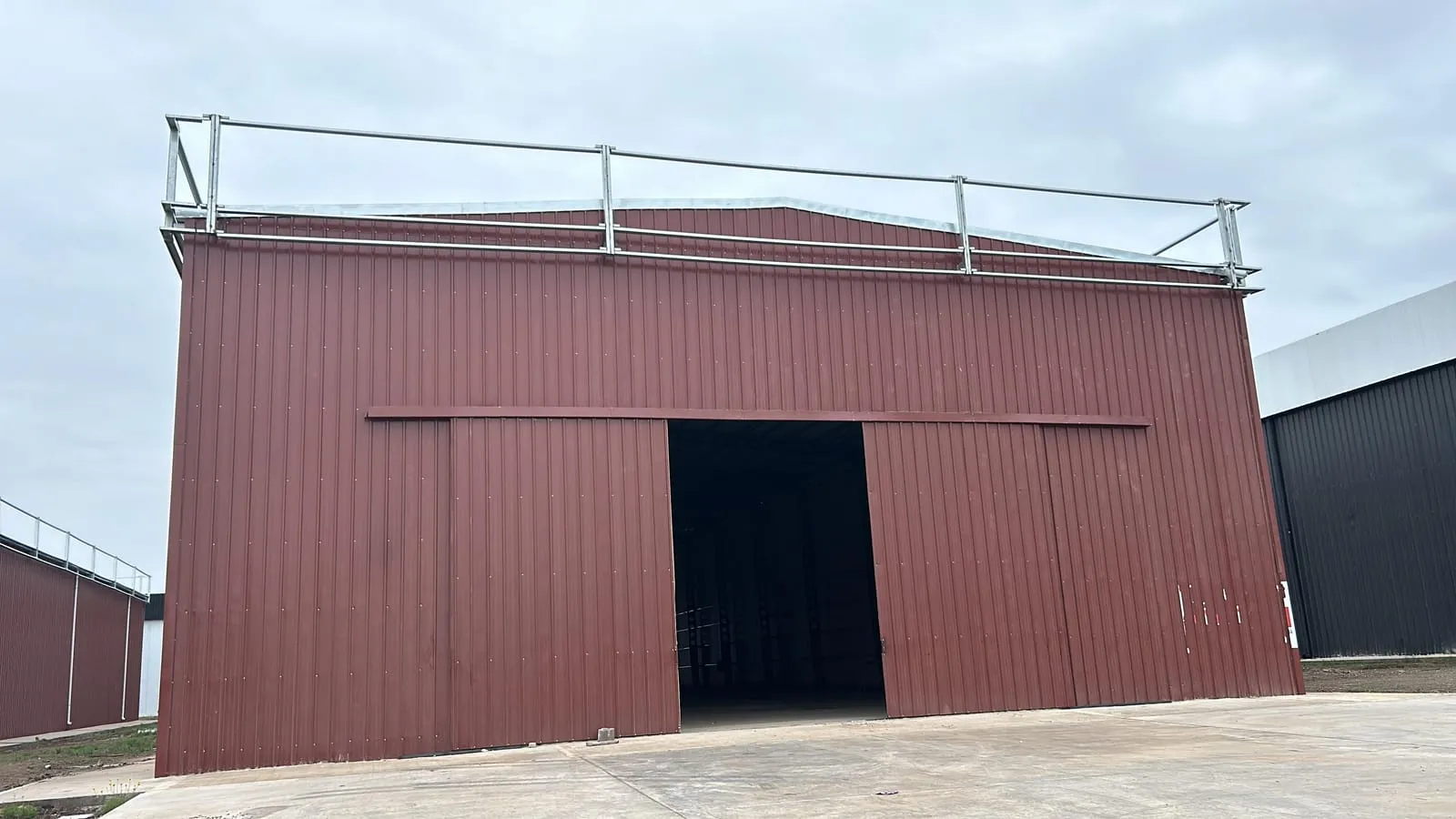 Nave industrial a dos aguas terminada, con cerramiento completo de chapa y portones corredizos abiertos