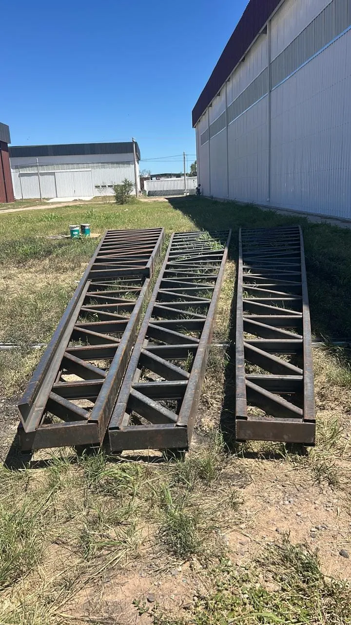 Vigas reticuladas de acero acopiadas en obra al pie de una nave terminada